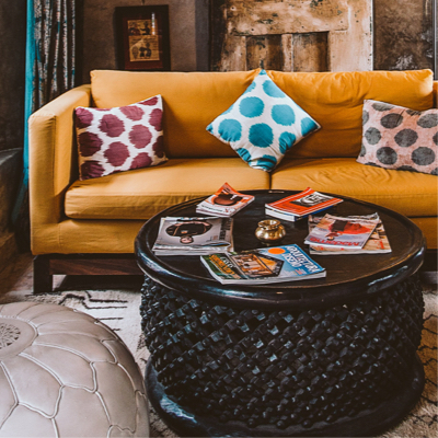 living room photo with orange couch and coffee table containing magazines on top